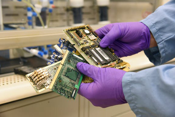 photo of person wearing purple gloves holding waste electronics