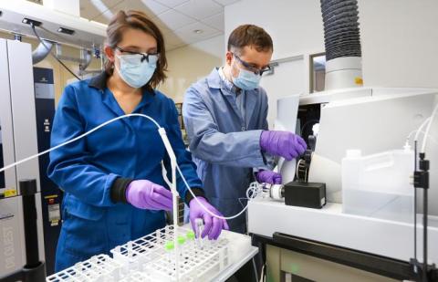 Two people work in a science laboratory: Santa Jansone-Popova (L) and Ilja Popovs quantify rare-earth element concentrations in liquid samples using spectroscopy (Courtesy Genevieve Martin/ORNL, US DOE)