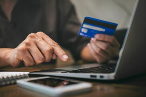 man on laptop holding credit card