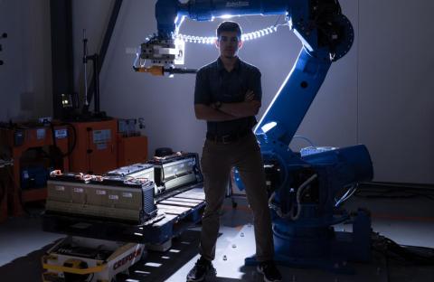 image of person standing with laboratory equipment: Jonathan Harter, a technical professional in ORNL’s Energy Science and Technology Directorate, uses a robot and other automated methods to disassemble electric vehicle batteries for recycling or reuse in the electric grid. Credit: Carlos Jones/ORNL, U.S. Dept. of Energy