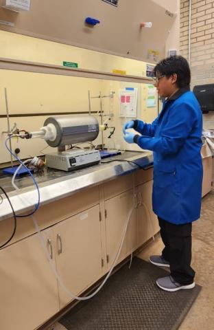 image of person wearing blue lab coat working in a science lab