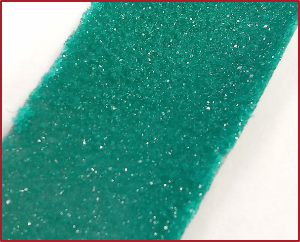 image of sample is sparkly green, shows solid product on stainless-steel nucleation scaffold 