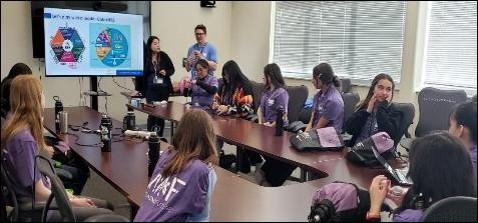 two people standing by girls seated at table: Introducing what are critical  materials and rare earth elements
