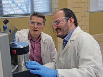 image of two people wearing white lab coats, with laboratory equipment