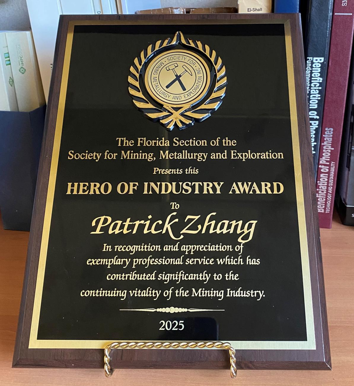 image of plaque with a seal and text: The Florida Section of the Society for Mining, Metallurgy and Exploration Presents this Hero of Industry Award to Patrick Zhang in recognition and appreciation of exemplary professional service which has contributed significantly to the continuing vitality of the Mining Industry, 2025