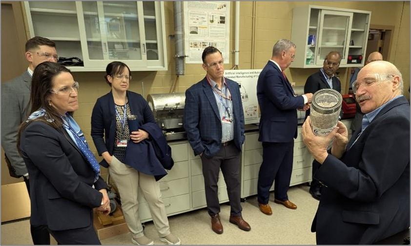 CMI Director Tom Lograsso, Ames National Laboratory (shown holding vial), describes CMI research from the Controlled Atmosphere Materials Processing System (CAMPS) laboratory to U.S. Department of Energy senior leadership, including Audrey Robertson, DOE Assistant Secretary of Energy (EERE), Office of Critical Minerals and Energy Innovation (CMEI) (shown left), with Ames National Laboratory Director Karl Mueller (shown right). 