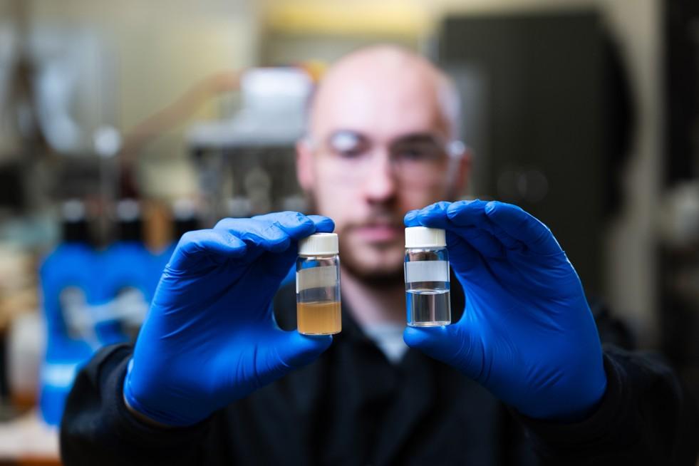 Post‑baccalaureate fellow Dex Altavilla displays the HREE‑loaded organic product (left) and the LREE aqueous concentrate (right) produced during the centrifugal contactor run.