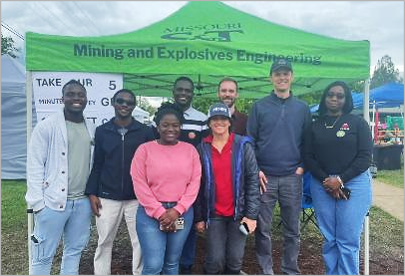 half a dozen people standing by a green awning