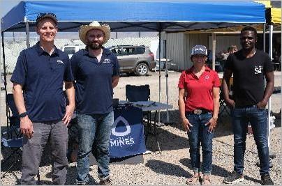 four people standing under blue awning