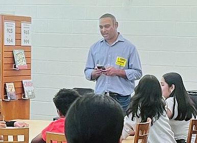 image of person standing, talking to middle school students in a library