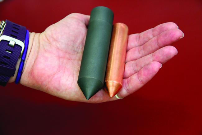 Ames Laboratory scientist Deborah Schlagel holds a graphite crucible (left) and a Bridgman-grown copper crystal (right).