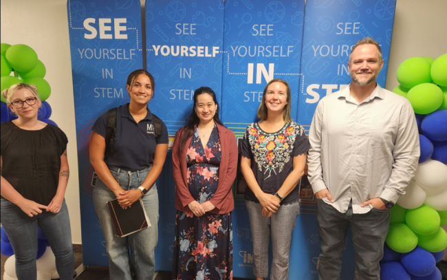 image of several people standing by a sign with text see yourself in STEM