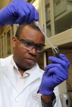 Ikenna Nlebedim looks at vial with liquid